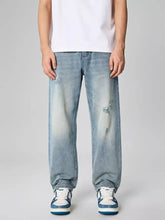 Men’s distressed relaxed fit light-wash denim jeans featuring faded patches and subtle frayed details