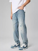 Men’s distressed relaxed fit light-wash denim jeans with faded distressing and subtle graphic prints on the thighs