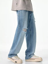 Men’s relaxed fit jeans in light-wash denim with distressed frayed patches on the knees for casual comfort