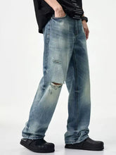 Men’s distressed relaxed fit jeans in light-wash denim with intentional knee rips and faded worn-in detailing