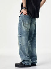 Men’s distressed relaxed fit light-wash denim jeans with a wide-leg cut and subtle distressing details