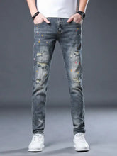 Men’s distressed slim fit dark-wash denim jeans with ripped details and colorful paint splatter accents
