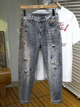 Men’s distressed slim fit gray denim jeans with ripped detailing and yellow paint splatter accents