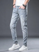Men’s light-wash slim fit jeans with distressed ripped details on thighs and knees in denim material