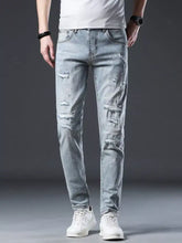 Men’s distressed slim fit light-wash denim jeans with ripped details and subtle white paint splatter accents