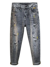 Men’s distressed slim fit dark gray denim jeans with intentional rips and yellow paint splatters fit jeans