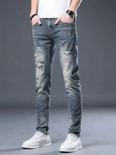 Men’s distressed slim fit dark wash denim jeans with colorful paint splatter accents and ripped knee details