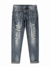 Men’s distressed slim fit gray denim jeans with colorful paint splatter accents and ripped knee details