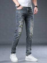 Men’s distressed slim fit gray denim jeans with colorful paint splatter accents and ripped knee details