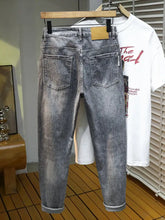 Men’s slim fit distressed gray denim jeans with faded wash and rolled cuffs for a modern fit look