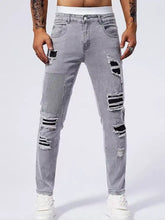 Men’s distressed slim fit jeans in gray denim featuring ripped patches and a striped fabric panel on the thigh