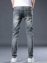 Men’s distressed slim fit light-wash denim jeans seen from the back with subtle fading and a brown leather brand tag