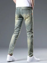 Men’s distressed slim fit light-wash denim jeans with white and orange paint splatter accents in slim fit style