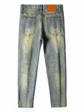 Men’s distressed slim fit light-wash denim jeans with paint splatter design in orange and silver specks