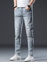 Men’s distressed slim fit jeans in light wash denim with ripped details and subtle white speckles visible from the front