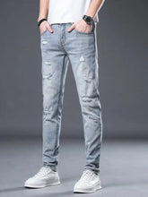 Men’s light-wash slim fit jeans with distressed ripped details on thighs and knees in denim material