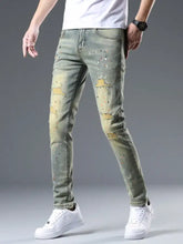 Men’s distressed slim fit olive green denim jeans with intentional rips and splattered paint accents
