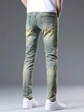 Men’s distressed slim fit jeans in light green denim with a slim fit and white and orange paint splatter design