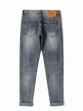 Men’s distressed slim fit light-wash denim jeans with rolled cuffs and brown leather patch at the waistband