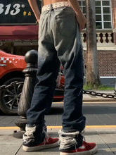 Men’s distressed wash loose fit dark-wash denim jeans with studded belt and frayed cuffs in a casual style