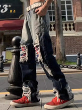 Men’s distressed wash loose fit denim jeans with ripped knees colorful lace-up detailing and studded belt