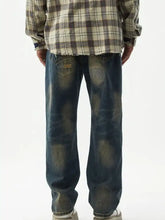 Men’s dark-wash denim jeans with a distressed wash, relaxed fit, wide leg, faded patches, and a frayed hem