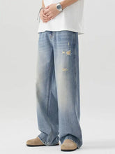 Men’s light-wash denim jeans with distressed faded patches and a relaxed wide-leg cut for casual wear
