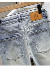 Back view of men’s distressed wide leg jeans in light wash denim with faded look and brown leather brand patch