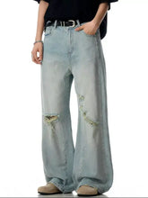 Men’s light-wash denim distressed wide leg jeans with frayed patches on the knees
