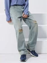 Men’s light-wash denim wide leg jeans with distressed and frayed knee patches in a relaxed straight-leg cut