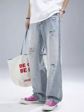 Men’s distressed wide leg jeans in light-wash denim with intentional rips and frayed edges visible from the front