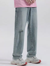 Light-wash denim men’s wide leg jeans with distressed knee patch and relaxed fit for casual wear