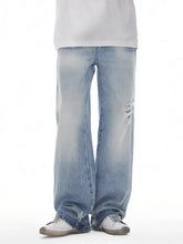 Men’s distressed wide leg jeans in light-wash denim with a relaxed fit and intentional distressing at the knees