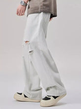 Men’s distressed wide leg jeans in light-wash denim with ripped knees and a relaxed straight-leg cut