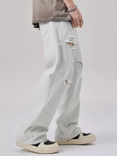 Men’s distressed wide leg jeans in light-wash denim with ripped details on the thighs and knees