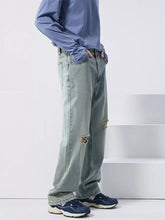 Men’s light-wash wide leg jeans with distressed ripped details on the thighs in denim fabric