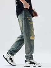 Men’s distressed wide leg relaxed fit jeans in faded blue denim with intentional knee rips and a relaxed fit silhouette