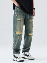 Men’s distressed wide leg relaxed fit jeans in faded blue wash with multiple ripped patches and a relaxed fit design