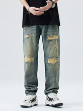 Men’s distressed wide leg relaxed fit jeans in faded blue denim with multiple ripped patches and frayed edges