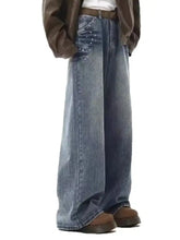 Men’s medium-wash blue denim wide leg jeans with subtle distressing and silver stud embellishments on front pocket