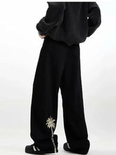 Men’s black wide-leg jeans with delicate silver embroidered palm tree on the lower leg for stylish comfort