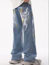 Men’s light-wash denim jeans with colorful yellow red and blue artistic splatter print in loose plus size fit