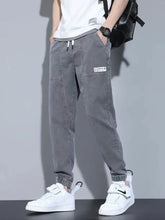 Men’s full size gray casual drawstring jeans with relaxed fit, elastic cuffs, and white label patch on the thigh