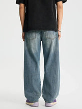 Men’s full size distressed relaxed fit baggy jeans in faded medium-blue denim with subtle whiskering and stitching details
