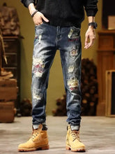 Men’s full size slim fit distressed wash blue denim jeans with colorful embroidered patches and ripped details