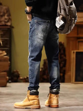 Worn blue denim slim fit jeans with distressed wash and frayed cuffs paired with tan timberland boots