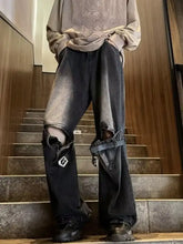 Men’s black distressed wide leg jeans with ripped knees and reinforced straps featuring wide leg buckled design