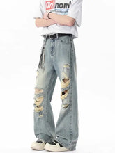 Men’s light-wash distressed wide leg jeans with ripped details and a beaded tassel on the side seam