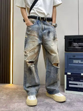 Men’s full size distressed wide leg jeans in faded blue denim with intentional knee rips and wide leg fit