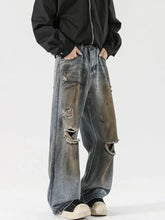 Men’s full size distressed wide leg denim jeans with faded blue and brown patches ripped knees and frayed edges